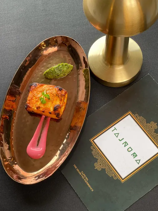 A starter served in a boat-shaped copper dish. Tajnuma, Agra.